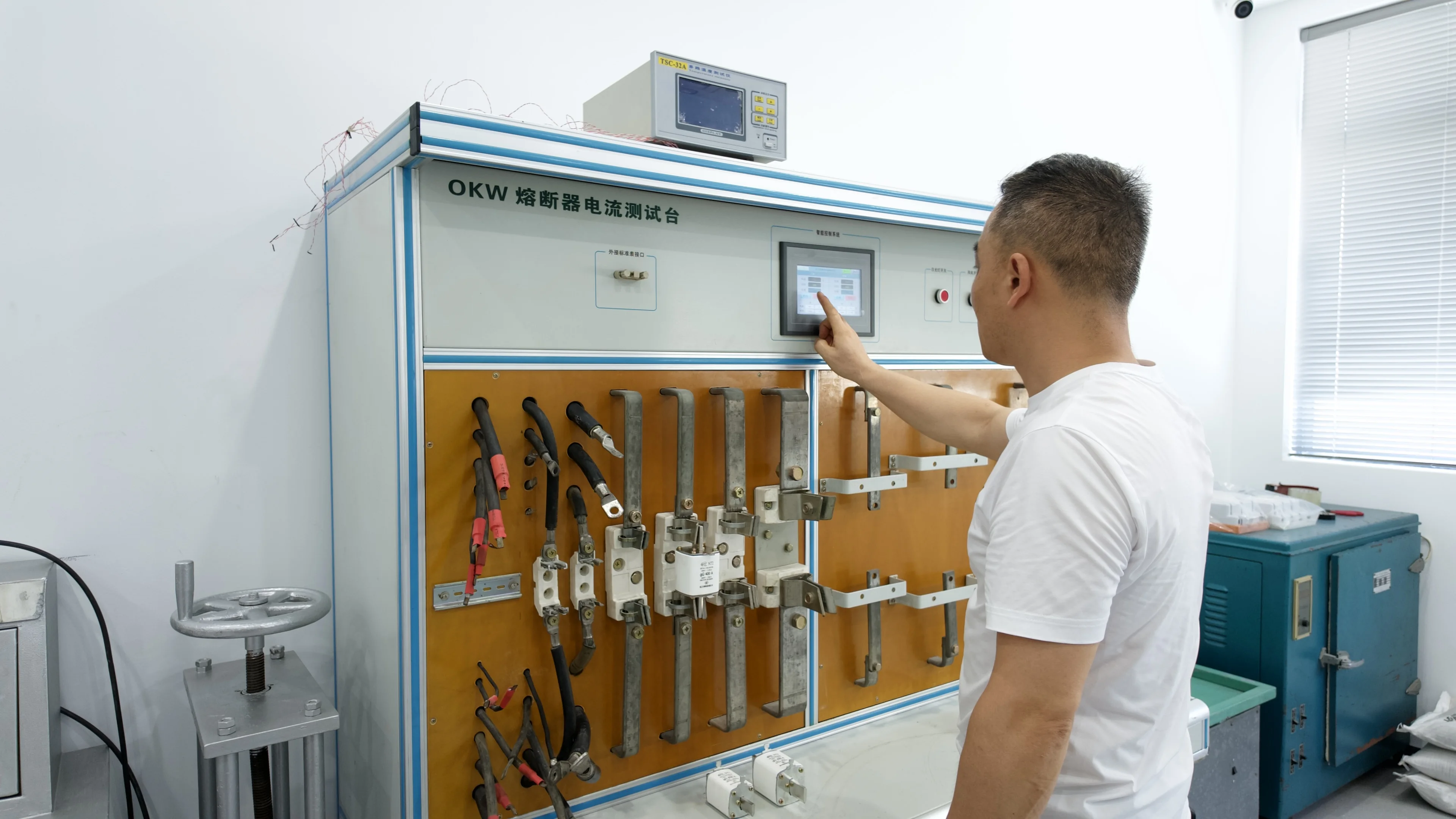 Technician operating fuse current test equipment in Xinglihui testing room