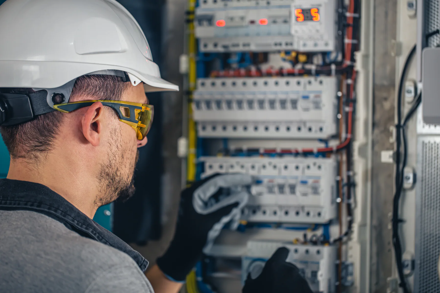 Electrical technician working with switchboard fuses
